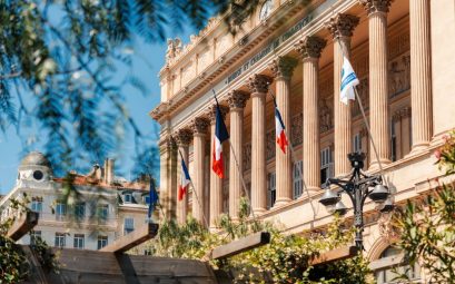 View of the historic Bourse et Chambre de Commerce building in Marseille with French flags.