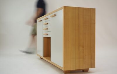 person walking beside white and brown wooden sideboard