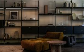 Modern living room with modular shelves and mustard armchair.