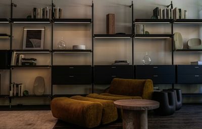 Modern living room with modular shelves and mustard armchair.