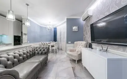 Modern light room with couch and TV on wall near armchair furnished with table and chairs next to cabinets