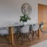 Elegant dining area with glass table, white chairs, parquet flooring, and wall decor.