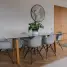 Elegant dining area with glass table, white chairs, parquet flooring, and wall decor.