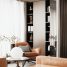 Elegant interior with an armchair, round lamp, and filled bookshelves.