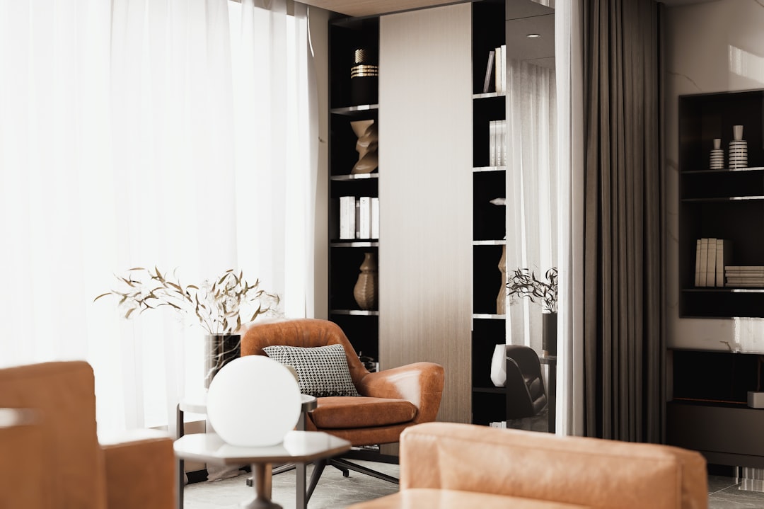 Elegant interior with an armchair, round lamp, and filled bookshelves.
