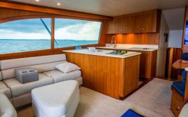 Spacious and elegantly designed yacht interior showcasing wooden furnishings and ocean view.