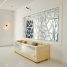 A beige sofa wrapped in plastic beneath a geometric mirror in a white room.