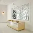 A beige sofa wrapped in plastic beneath a geometric mirror in a white room.