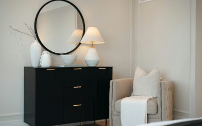 Black dresser with mirror and chair in a bedroom
