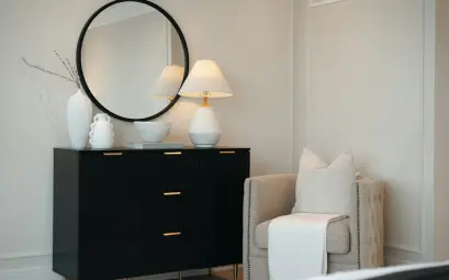 Black dresser with mirror and chair in a bedroom