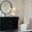 Black dresser with mirror and chair in a bedroom