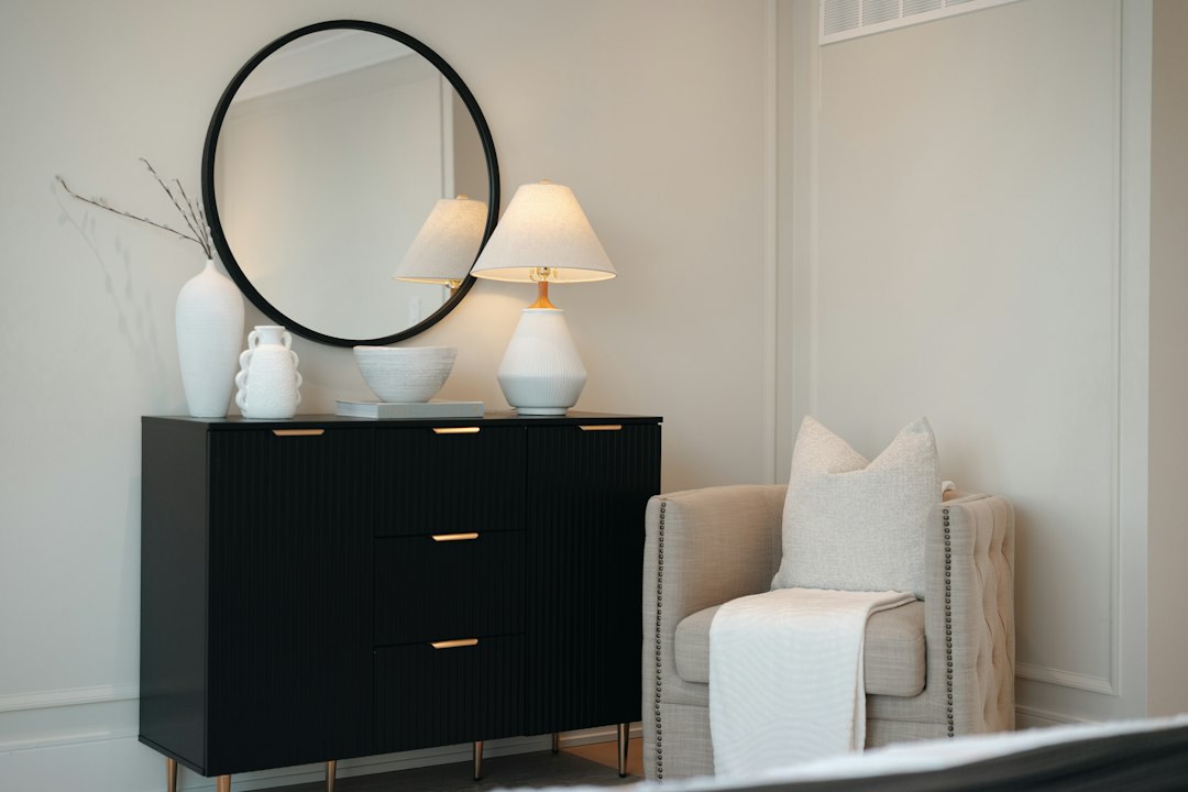 Black dresser with mirror and chair in a bedroom