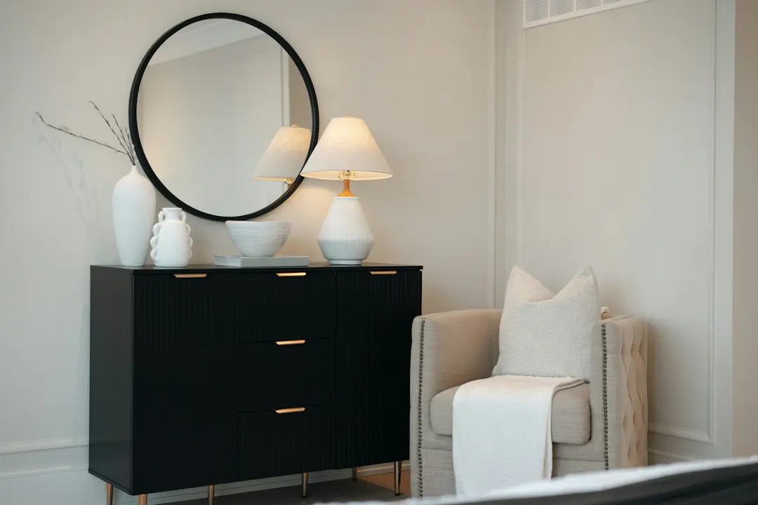 Black dresser with mirror and chair in a bedroom